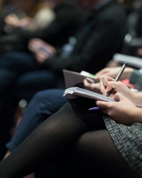 selective focus photography of people sitting on chairs while writing on notebooks