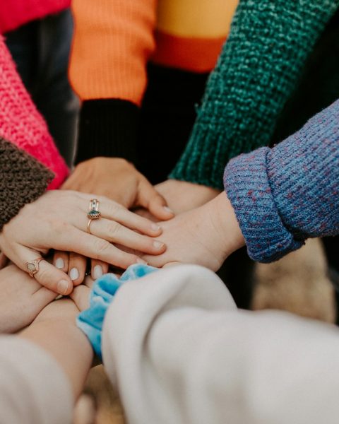 person in red sweater holding babys hand