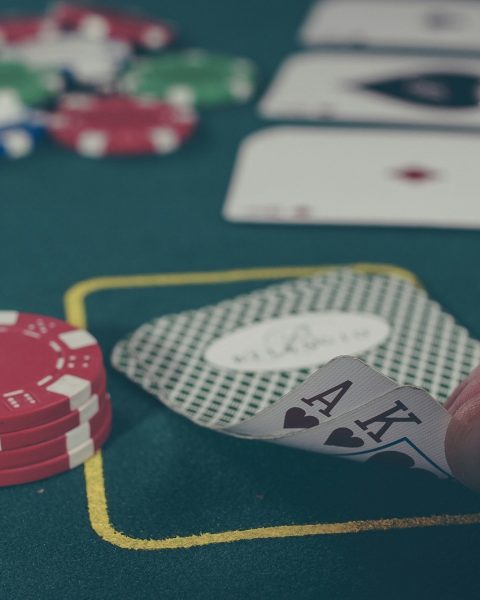 person holding black ace and king spades playing cards on poker table