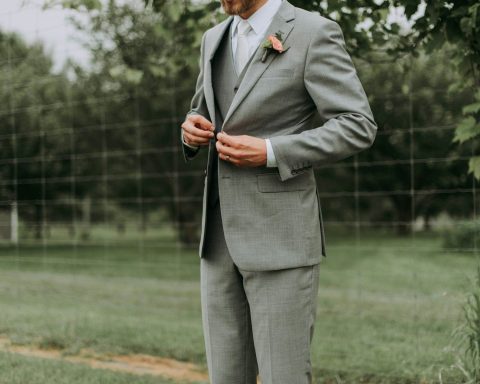 standing man holding his notched lapel suit jacket's button
