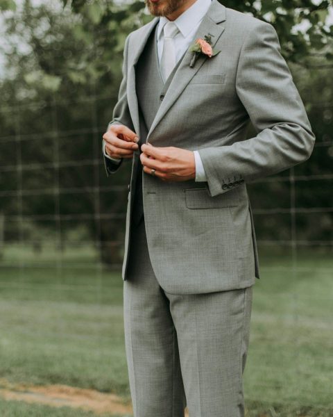 standing man holding his notched lapel suit jacket's button
