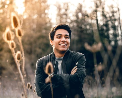 smiling man standing near green trees