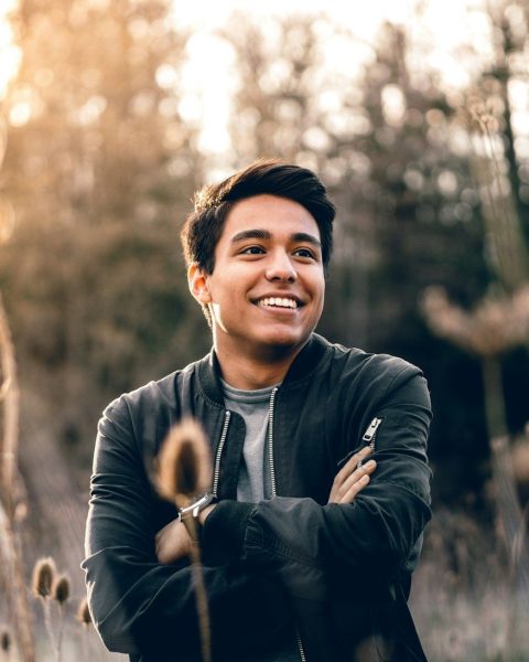 smiling man standing near green trees