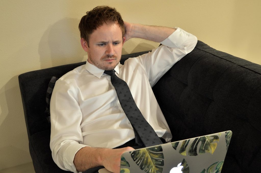 Jonge man werkt op laptop thuis naast zijn vaste baan