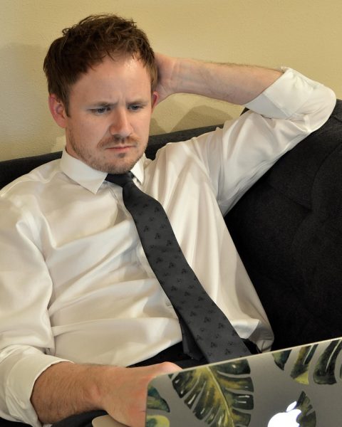 Jonge man werkt op laptop thuis naast zijn vaste baan