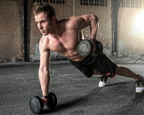 Jonge man in eenvoudige trainingskleding tijdens een krachttraining in de gym