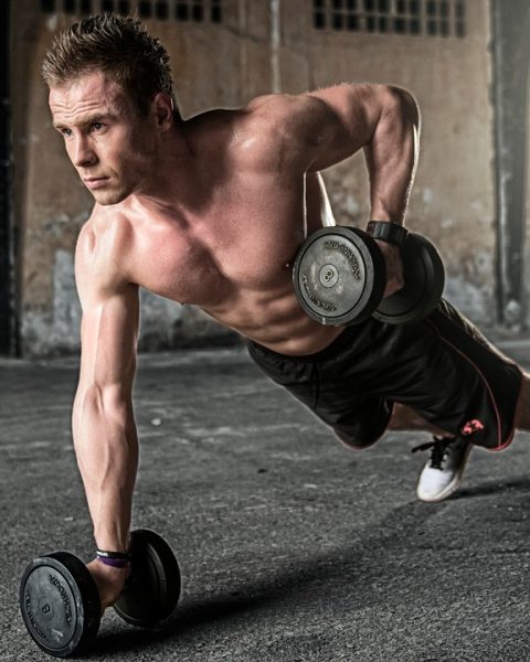 Jonge man in eenvoudige trainingskleding tijdens een krachttraining in de gym