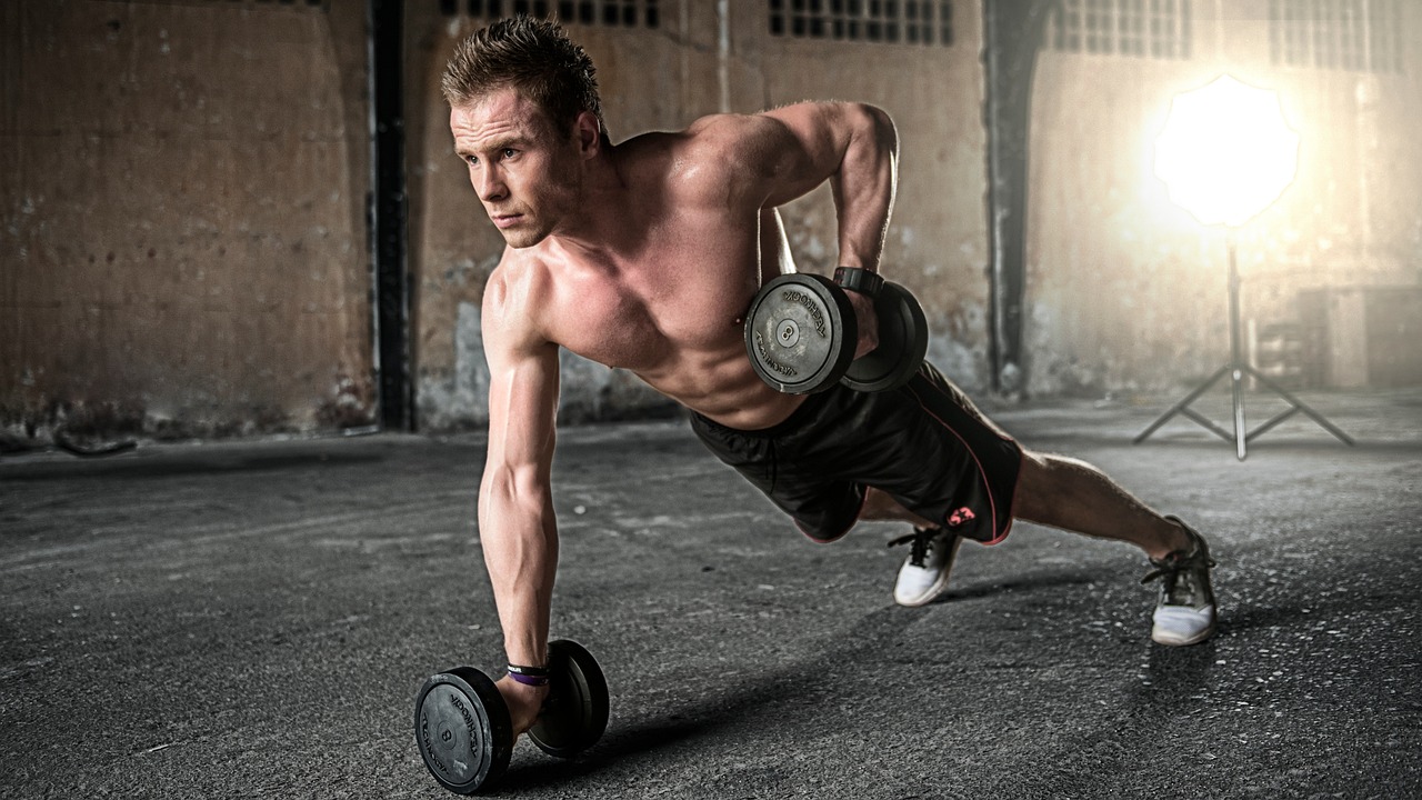Jonge man in eenvoudige trainingskleding tijdens een krachttraining in de gym