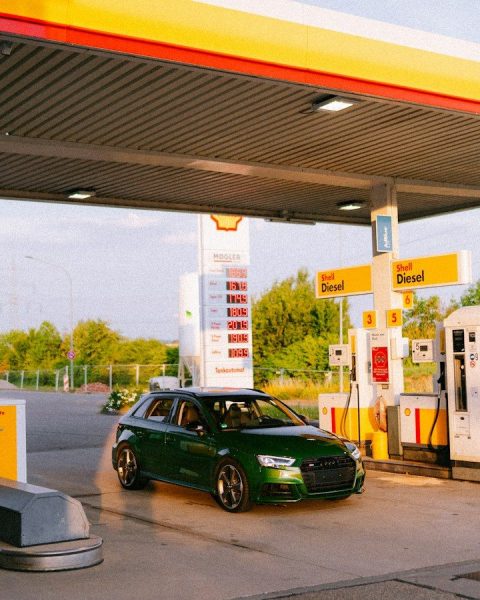 A green car parked at a shell gas station