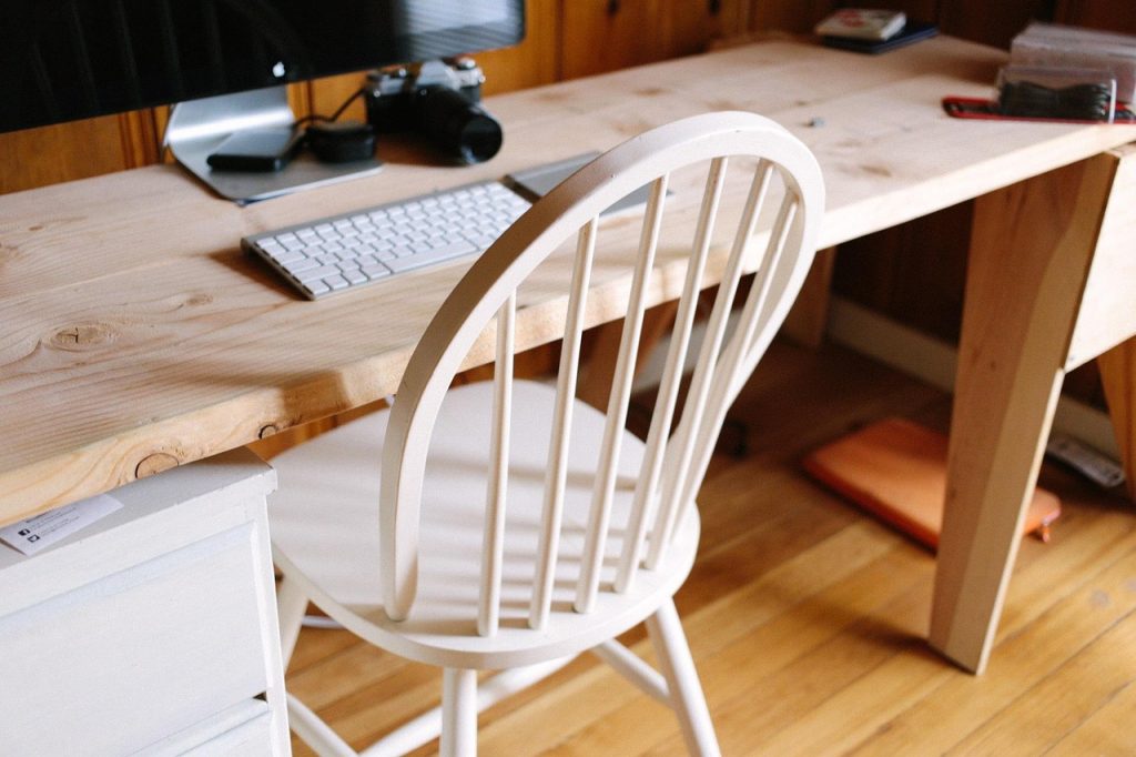 Nette thuiswerkplek met monitor, lamp en stoel op een klein bureau