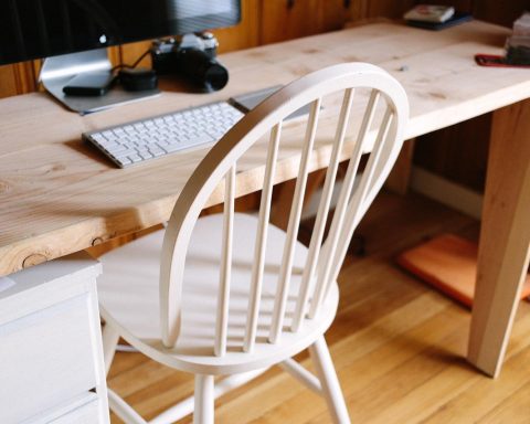 Nette thuiswerkplek met monitor, lamp en stoel op een klein bureau