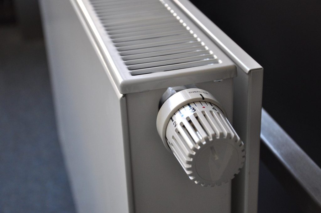 Hand met ontluchtingssleutel bij het ventiel van een radiator
