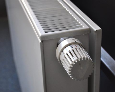 Hand met ontluchtingssleutel bij het ventiel van een radiator