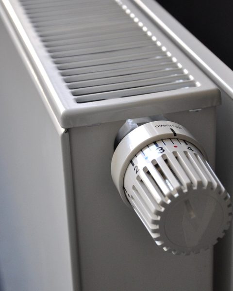 Hand met ontluchtingssleutel bij het ventiel van een radiator