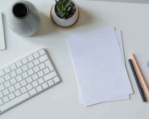 white printer paper beside white apple keyboard
